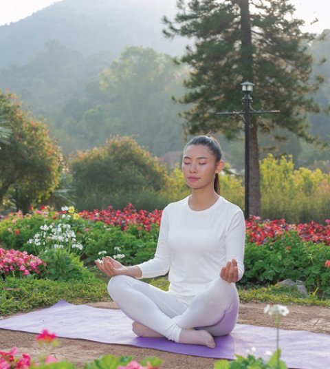 Guest practicing yoga and meditation at Ojaswi Resort in Mukteshwar, surrounded by lush gardens and Himalayan nature for wellness and relaxation